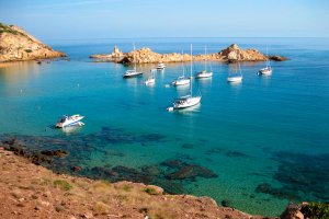 Cala Pregonda con aguas cristalinas y varios barcos varados por la zona. no-movil